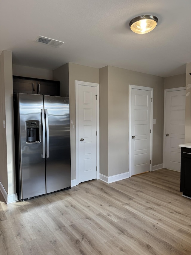 kitchen with stainless steel fridge with ice dispenser, dark brown cabinetry, and light hardwood / wood-style floors