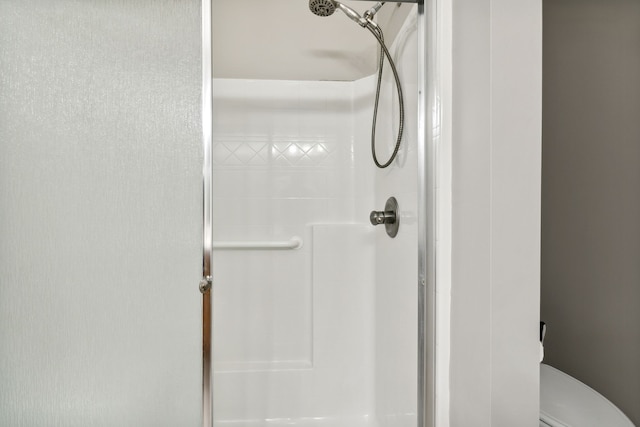 bathroom featuring tiled shower and toilet