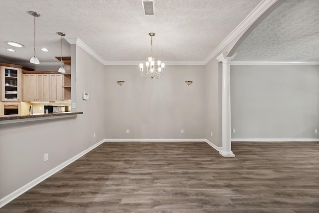 unfurnished dining area with ornate columns, dark hardwood / wood-style floors, sink, ornamental molding, and a textured ceiling