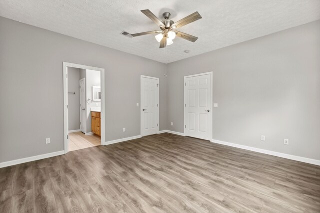 unfurnished bedroom with ensuite bath, a textured ceiling, ceiling fan, and light wood-type flooring