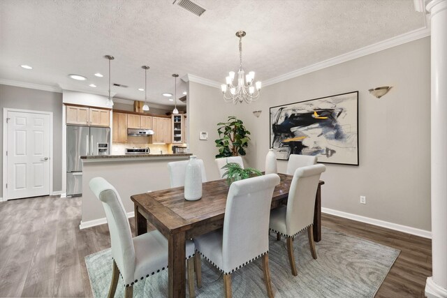 dining room with a textured ceiling, wood-type flooring, and ornamental molding