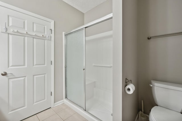 bathroom featuring tile patterned flooring, a shower with shower door, a textured ceiling, and toilet