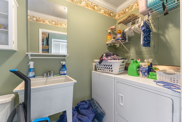 clothes washing area featuring sink, crown molding, and washer and clothes dryer