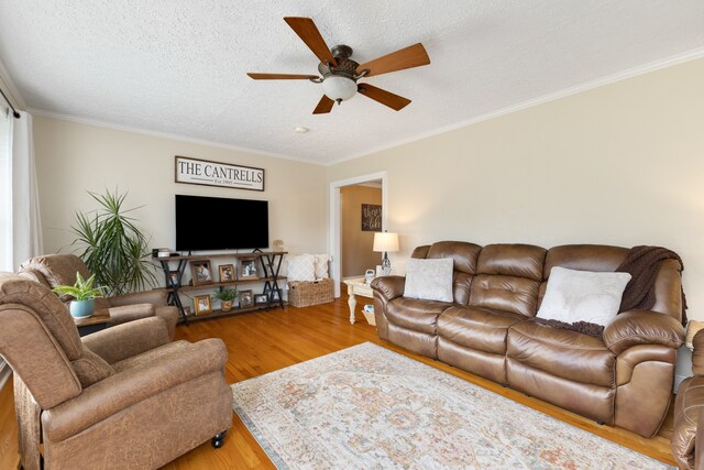 living room featuring ceiling fan, crown molding, a textured ceiling, and light hardwood / wood-style floors