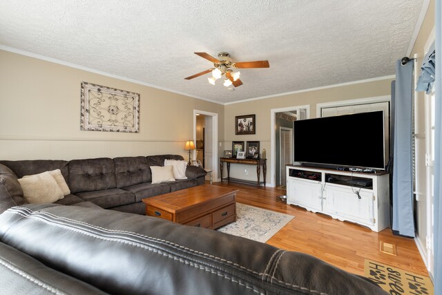 living room with ceiling fan, light wood-type flooring, a textured ceiling, and crown molding