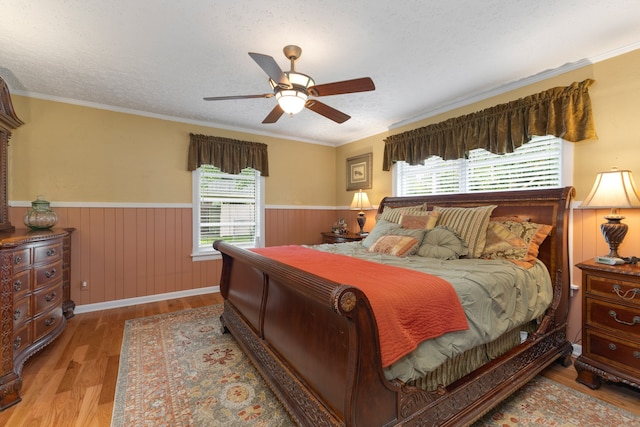 bedroom featuring light hardwood / wood-style floors, crown molding, ceiling fan, and a textured ceiling