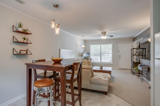 dining room with crown molding, ceiling fan, and light carpet