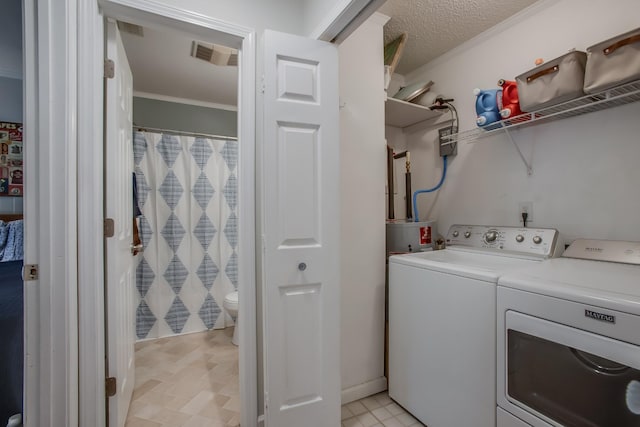 clothes washing area with ornamental molding, independent washer and dryer, and a textured ceiling