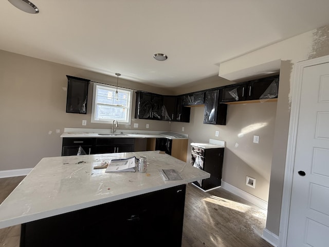 kitchen with a center island, sink, hanging light fixtures, dark hardwood / wood-style floors, and light stone countertops