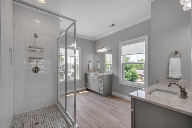 bathroom with wood-type flooring, a shower with door, a healthy amount of sunlight, and ornamental molding