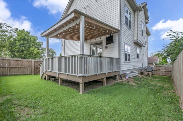 rear view of property featuring a deck, cooling unit, and a yard