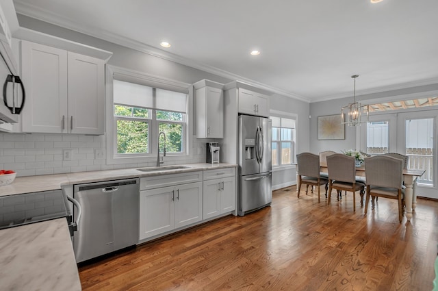 kitchen featuring hardwood / wood-style floors, appliances with stainless steel finishes, decorative backsplash, and a wealth of natural light