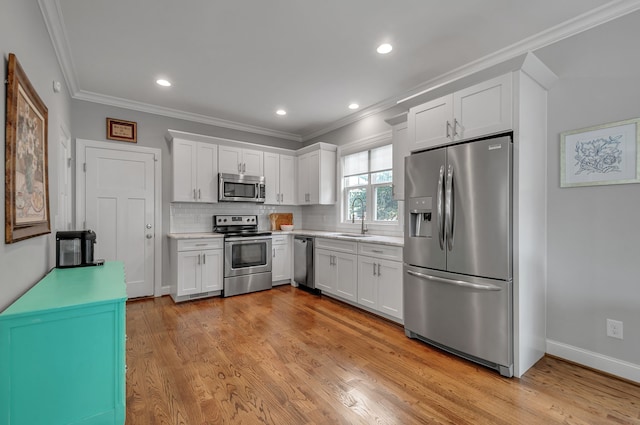 kitchen with stainless steel appliances, decorative backsplash, light wood-type flooring, and white cabinets