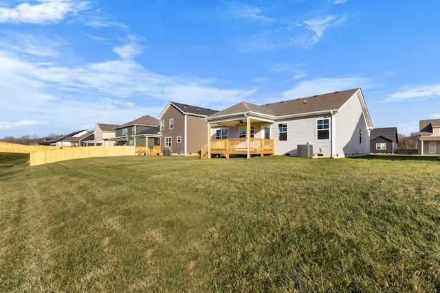 rear view of house with ceiling fan, a wooden deck, cooling unit, and a lawn