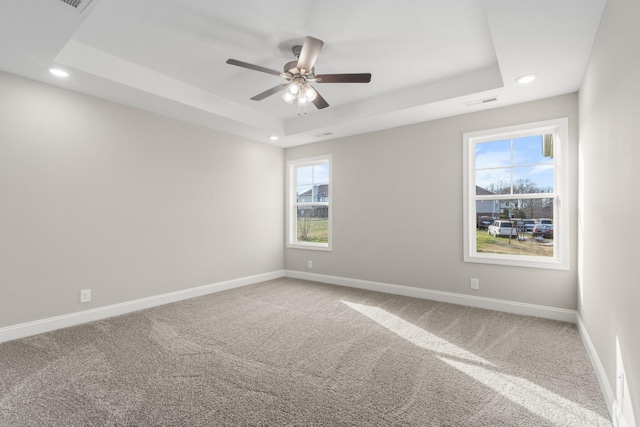 empty room featuring carpet flooring, ceiling fan, and a tray ceiling