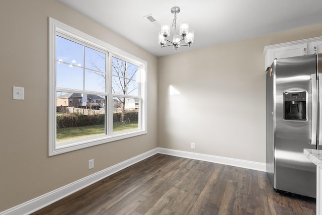 unfurnished dining area with dark hardwood / wood-style flooring and a chandelier