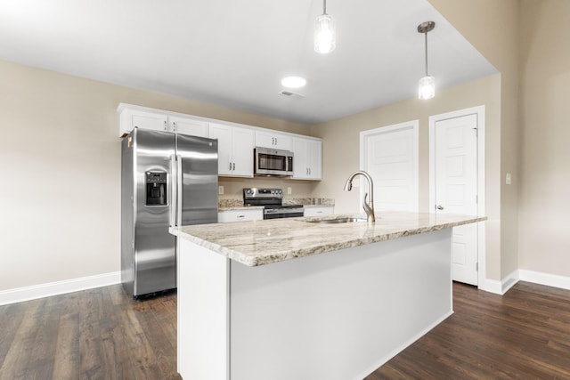 kitchen with hanging light fixtures, a center island with sink, white cabinetry, appliances with stainless steel finishes, and sink