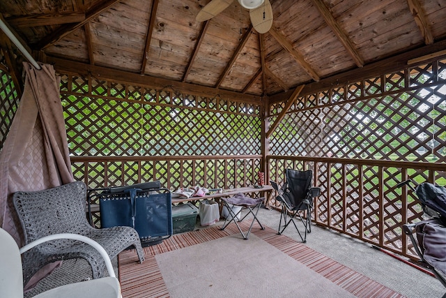 unfurnished sunroom with lofted ceiling with beams, wood ceiling, and ceiling fan