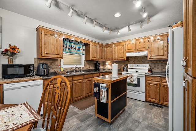 kitchen with tasteful backsplash, white appliances, sink, and a center island