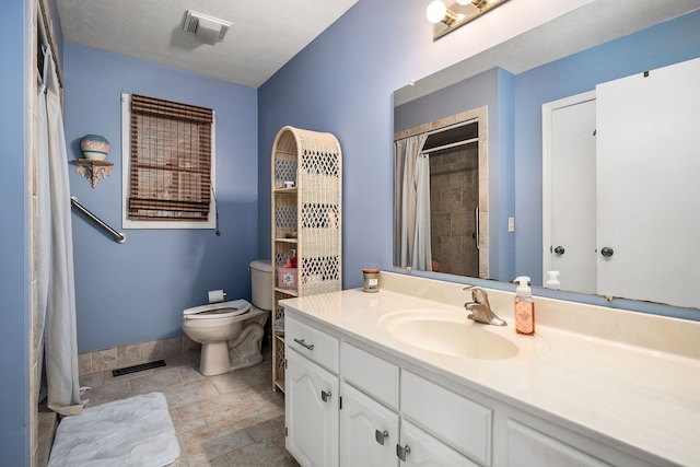 bathroom with tile patterned floors, vanity, a textured ceiling, and toilet