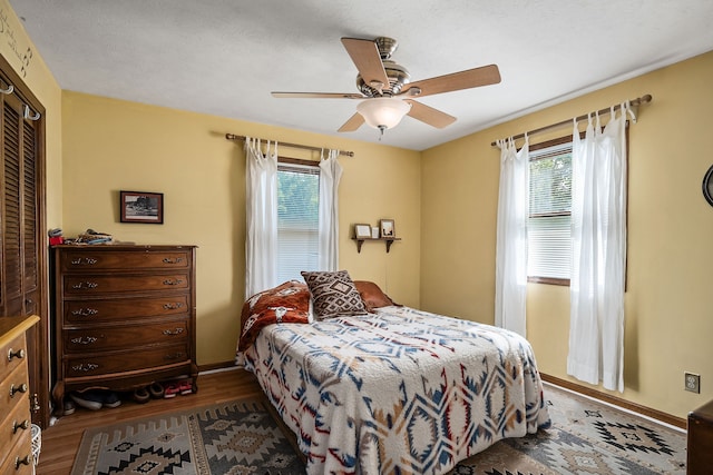 bedroom with hardwood / wood-style floors, a closet, multiple windows, and ceiling fan