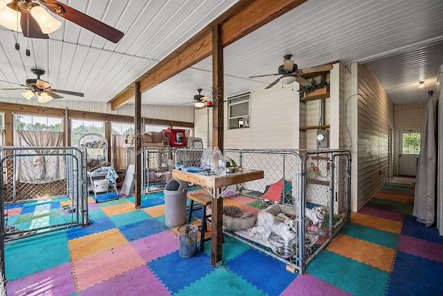 exterior space with beam ceiling, ceiling fan, and a wealth of natural light