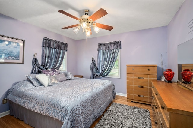 bedroom with light wood-type flooring, ceiling fan, and multiple windows