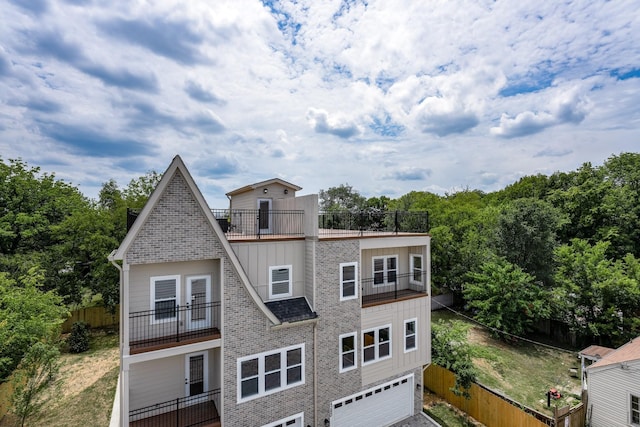 view of front of home featuring a garage, board and batten siding, fence, and a balcony