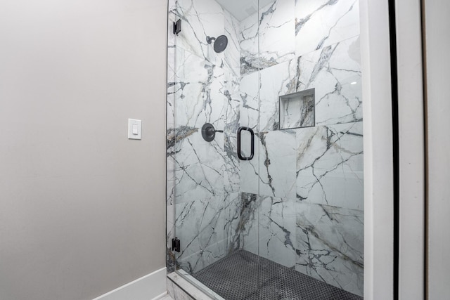 full bathroom featuring a marble finish shower and baseboards