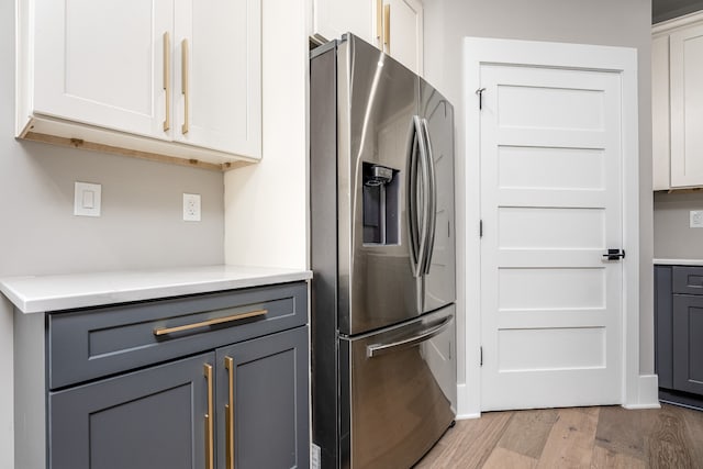 kitchen with stainless steel fridge with ice dispenser, white cabinets, light hardwood / wood-style flooring, and gray cabinetry