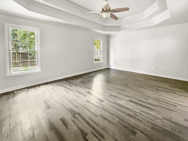 spare room featuring dark hardwood / wood-style flooring, a tray ceiling, ornamental molding, and ceiling fan