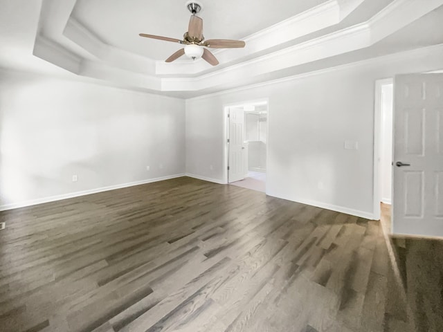 empty room featuring a raised ceiling, ornamental molding, dark wood-type flooring, and ceiling fan