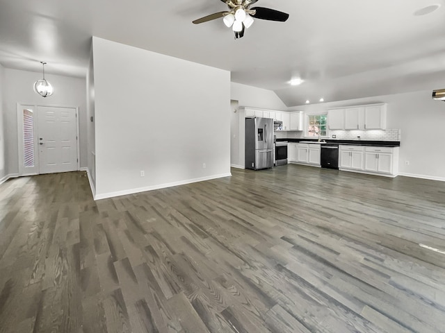 unfurnished living room featuring dark hardwood / wood-style flooring, vaulted ceiling, and ceiling fan