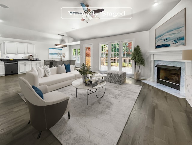 living room featuring ceiling fan, dark hardwood / wood-style floors, a premium fireplace, and vaulted ceiling