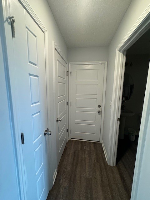 corridor featuring dark hardwood / wood-style flooring and a textured ceiling