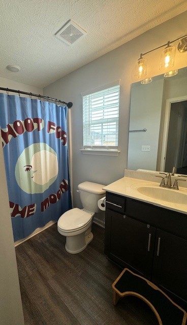 bathroom with a textured ceiling, toilet, vanity, and hardwood / wood-style flooring