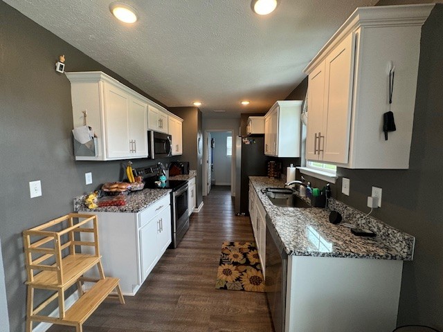 kitchen featuring dark hardwood / wood-style flooring, appliances with stainless steel finishes, sink, white cabinetry, and stone counters