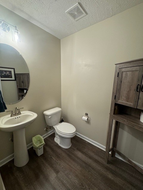 bathroom featuring a textured ceiling, toilet, and hardwood / wood-style flooring