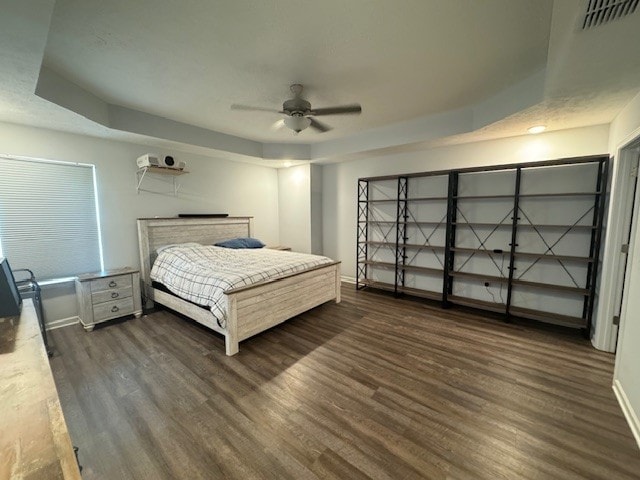 bedroom featuring ceiling fan, a tray ceiling, and dark hardwood / wood-style floors