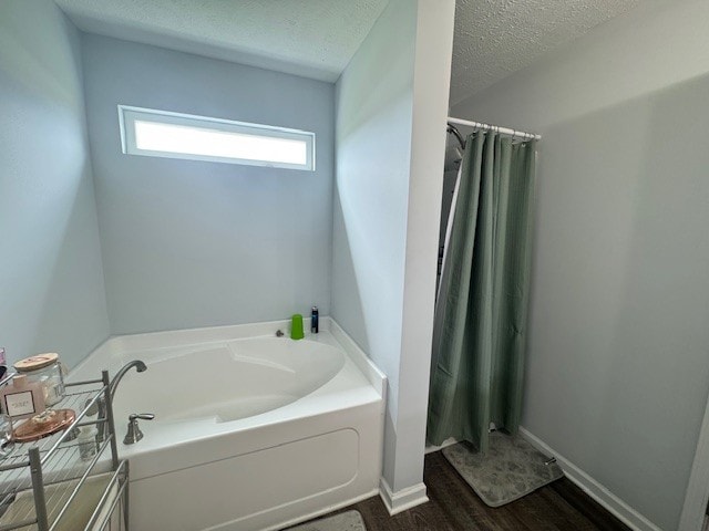 bathroom with a textured ceiling, a bathing tub, and wood-type flooring