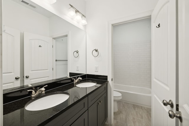 full bathroom featuring toilet, dual bowl vanity, tile patterned flooring, and tiled shower / bath combo