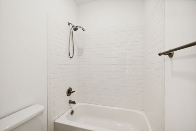 bathroom featuring tiled shower / bath combo and toilet