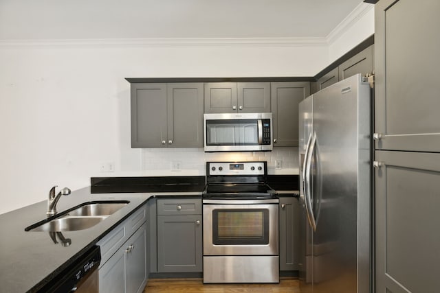 kitchen featuring appliances with stainless steel finishes, crown molding, light hardwood / wood-style floors, gray cabinetry, and sink