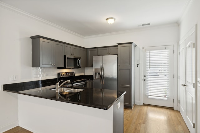 kitchen with light hardwood / wood-style flooring, appliances with stainless steel finishes, plenty of natural light, and kitchen peninsula