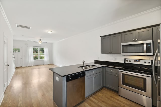 kitchen featuring stainless steel appliances, light hardwood / wood-style floors, ceiling fan, sink, and kitchen peninsula