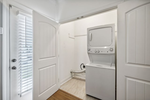 laundry room featuring light wood-type flooring and stacked washer / drying machine