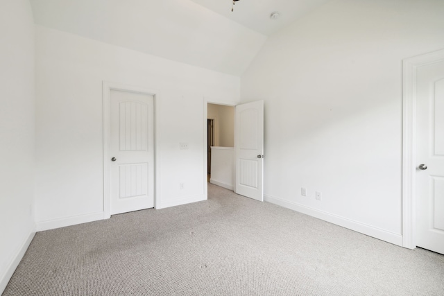 unfurnished bedroom featuring lofted ceiling and carpet floors