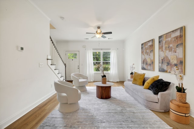 living room featuring ceiling fan, light wood-type flooring, and ornamental molding