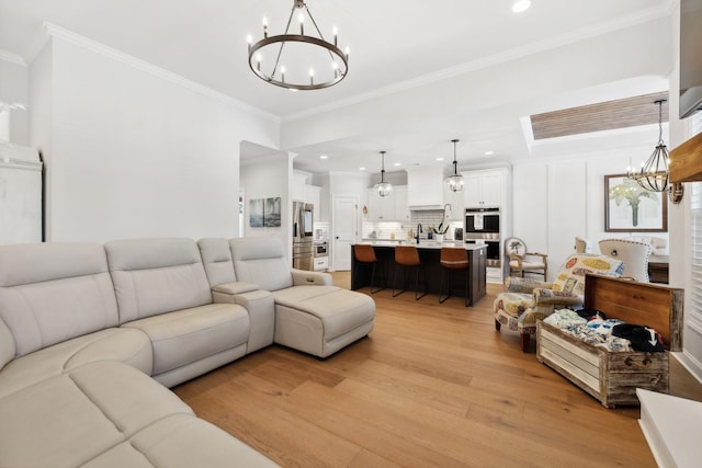 living area with an inviting chandelier, ornamental molding, light wood finished floors, and recessed lighting