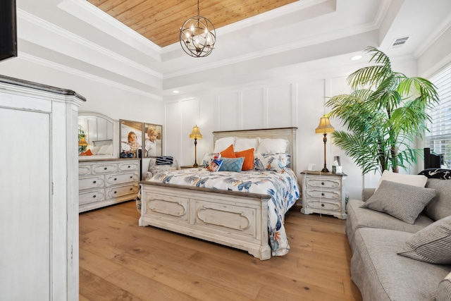 bedroom with a notable chandelier, a raised ceiling, ornamental molding, and light wood-type flooring